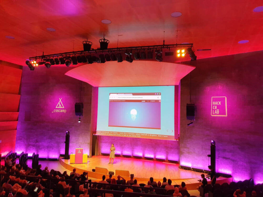 Cassie on stage at CSS camp in barcelona. Screen behind her shows an SVG jellyfish.